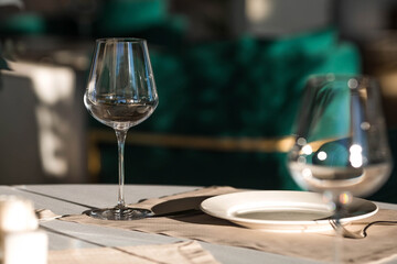 Stylish table setting. Glass glasses, plates, cutlery on the table. Wedding service, reception at the dining table. A birthday, a baptism, a festive event.