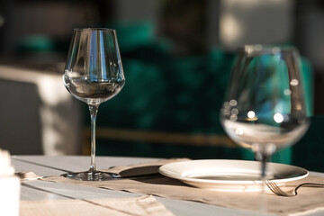Stylish table setting. Glass glasses, plates, cutlery on the table. Wedding service, reception at the dining table. A birthday, a baptism, a festive event.