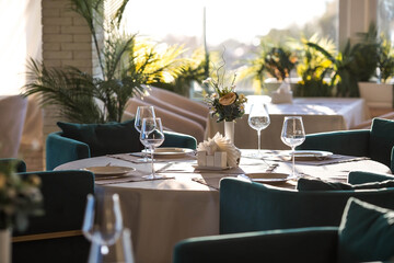 Stylish table setting. Glass glasses, plates, cutlery on the table. Wedding service, reception at the dining table. A birthday, a baptism, a festive event.