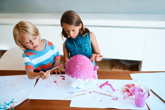 Painting, children and project in home for creativity, fun activity and design for arts and crafts. Messy, kids and creative on table for paper mache, DIY piggy bank and relationship development