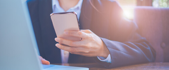 Close up,Businesswoman using mobile smart phone, working on laptop computer at office.For web banner.