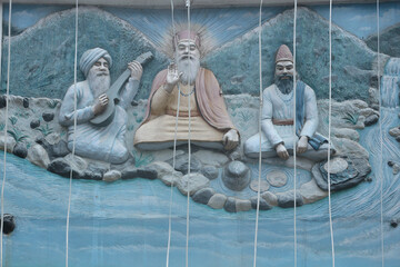 Guru Nanak and his two companions. Bas-relief on the wall of the Sikh temple in Manikaran, Northern...