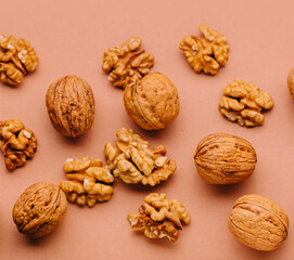 Walnuts in shell and peeled are lying on a brown background