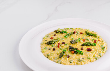 Creamy risotto with asparagus and bacon on white plate