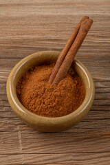 one stick in ground cinnamon in a bowl on wooden table