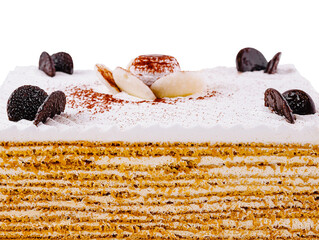 Delicious multi layered honey cake decorated with chocolate and white cream standing on white...