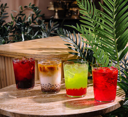 Four colorful summer cocktails resting on a stone tabletop in a tropical setting