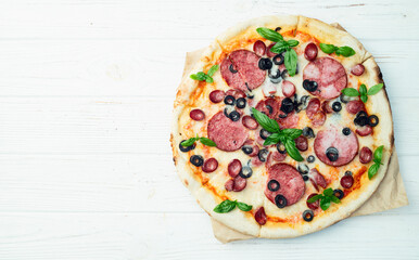 Pizza with mozzarella cheese , salami sausages , olives , and basil