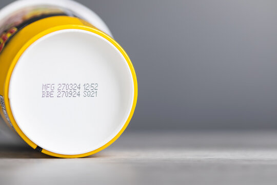 Production and expiration codes printed beneath a clear food container of instant noodles. The image highlights the importance of checking product dates for safety and quality