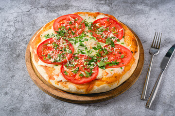 Neapolitan Margherita pizza with tomatoes, mozzarella, basil and olives on stone table
