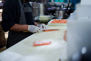 Chef use knife preparing a fresh salmon on a cutting board, Japanese chef in restaurant slicing raw salmon, ingredient for seafood dish. Chef with a knife cutting raw salmon