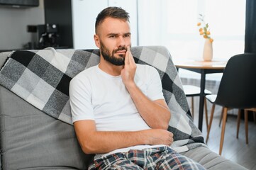 Young man suffering from toothache at home