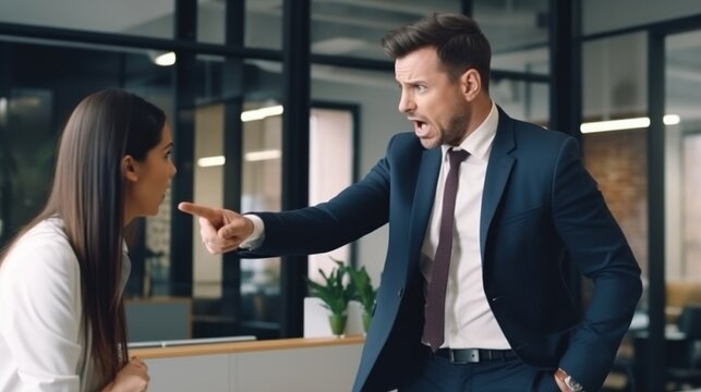 A man in a suit aggressively points and shouts at a woman in an office setting, capturing a moment of conflict and tension while the woman looks surprised.