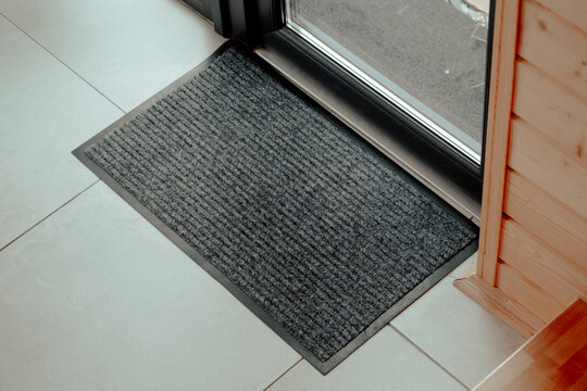 A textured black doormat placed at the entrance of a contemporary home capturing the warmth of indoor comfort and welcoming ambiance on a sunny day