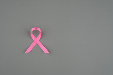 Pink ribbon placed on a gray surface symbolizing support for breast cancer awareness campaigns