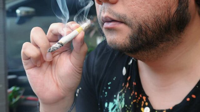 a man smoking a kretek cigarette on the front porch of his house