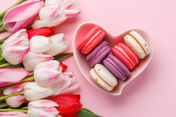 Pastel colorful tulips and vibrant macaroons fill a heart-shaped bowl
