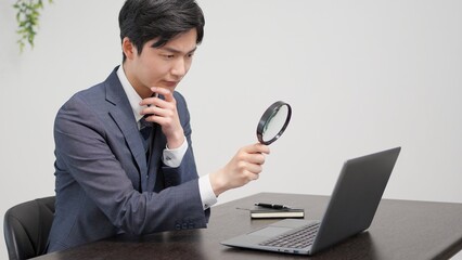 虫眼鏡で調査をするビジネスマン