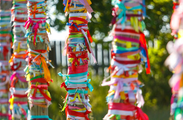 Multicolored ribbons hang on wooden poles. Religion