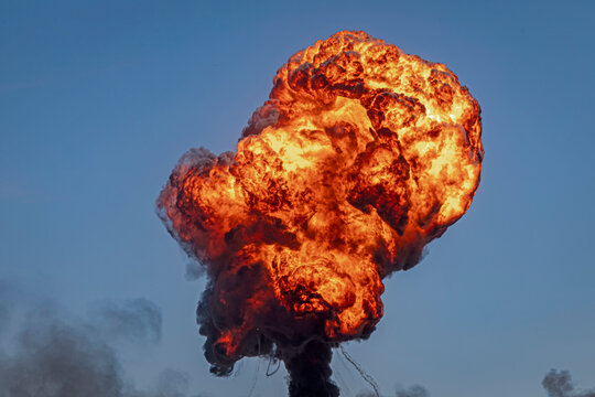 A large fireball from a munitions explosion against a blue sky