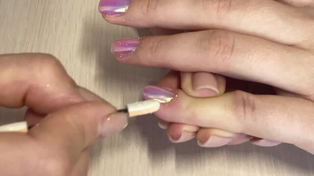 Manicure, close-up manicurist rubs nails with chrome powder, trendy nail art design with shiny metallic coating, nail salon services