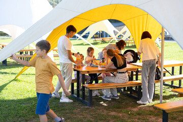 Family enjoying a picnic under yellow tents in the park