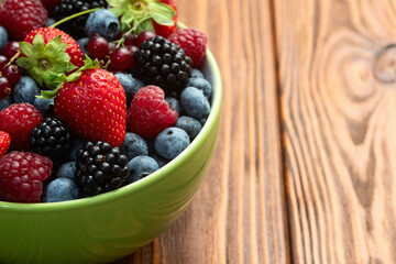 Mix of ripe colorful berries in bowl photography . Blueberry , strawberry , raspberry , blackberry and red currant . Top view