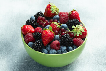 Mix of ripe colorful berries in bowl photography . Blueberry , strawberry , raspberry , blackberry and red currant . Top view
