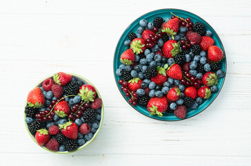 Mix of ripe colorful berries in bowl photography . Blueberry , strawberry , raspberry , blackberry and red currant . Top view