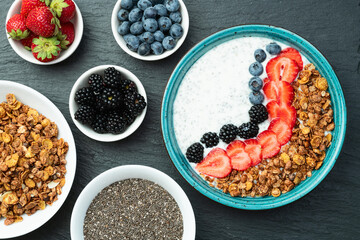 Healthy breakfast . Yogurt with berries ( strawberry , raspberry , blueberry , blackberry ) , granola and chia seeds . Top view