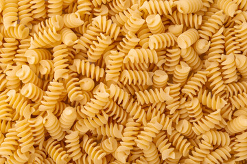 Fusilli background. A pile of yellow pasta in the shape of a spiral.
