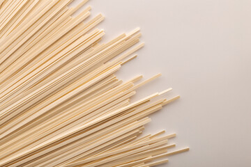 Flat wheat pasta on gray background with space for text.