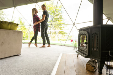 a couple in geo dome tents. Cozy, camping, glamping, holiday, vacation lifestyle concept. Outdoors cabin, scenic background.