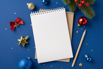 A top view of a blank notebook surrounded by festive Christmas decorations, including ornaments and...