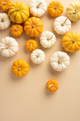 A collection of orange and white pumpkins scattered on a beige backdrop. Ideal for autumn, Thanksgiving, and seasonal themes with a warm, cozy feel