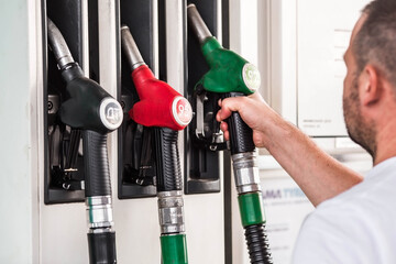 Gas station. Refueling the car with gasoline. A man holds a Russian fuel dispenser at a gas...