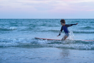 Happy child boy enjoyed surfing and splashing waves in the sea, summer vacation concept at sea