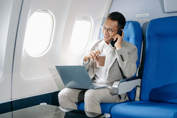 Asian man sitting in a seat in airplane and looking out the window going on a trip vacation travel concept.