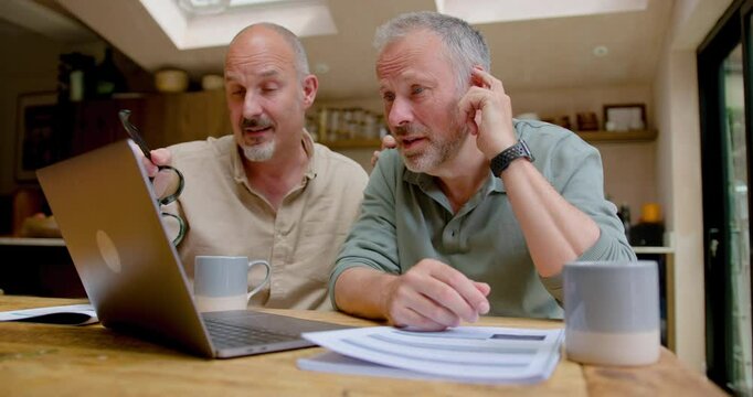 Happy Mature Male Gay Couple looking at Investments on Laptop computer for Retirement