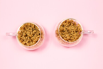 Dry elderberry flowers in glass cups on a pink background