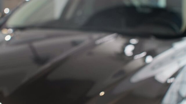 Famale hand gives a car keys to male hand in the car dealership close up. Unrecognized auto seller and a woman who bought a vehicle shake hands.