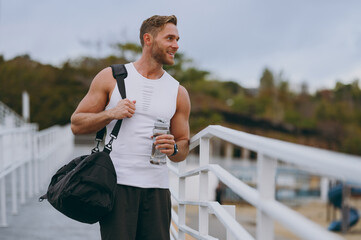 Side view young smiling strong sporty athletic toned fit sportsman man wears sports clothes bag...