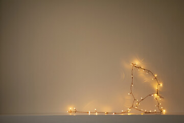 Yellow New Year's garlands against a plain wall background. Beautiful stylish minimalistic background for Christmas greetings and invitations
