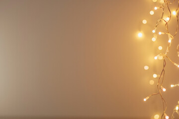 Yellow New Year's garlands against a plain wall background. Beautiful stylish minimalistic background for Christmas greetings and invitations