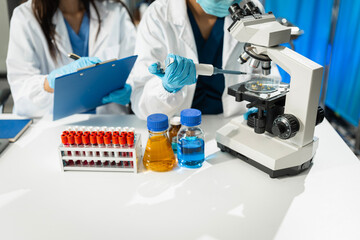 Chemist scientist holding test tube and tablet conducting experiment in laboratory with equipment,...