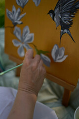 a beautiful young artist in a white dress paints a picture on the river bank