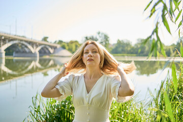 beautiful young artist in a white dress among the trees on the river bank