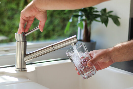 Close up of male hands pouring tap water into a glass in the kitchen