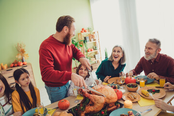 Photo of big family celebrating thanksgiving day together man cutting main traditional dish baked turkey indoors