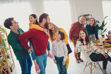 Photo of attractive cheerful big full family play together piggyback meeting eating holiday dinner good mood having fun at home indoors